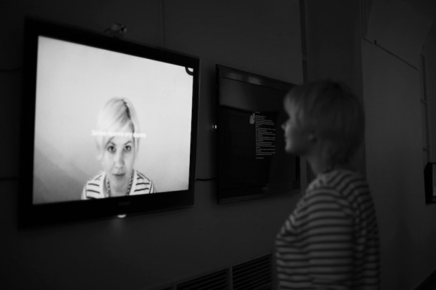 Installation, woman looking at a screen, with a woman looking back