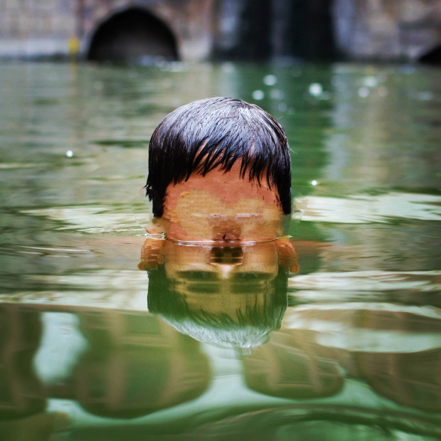 Image from the work: Photoshopped image of a boy rising from the water, facial features blurred.