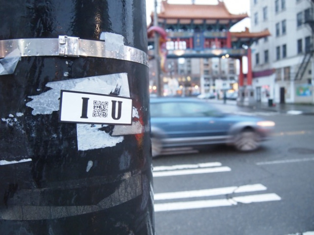 A sticker with the text I and You, with a QR code in between, stuck onto a pole outside China Town.
