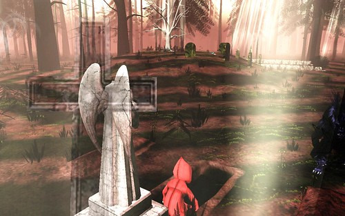 Gameplay: A small figure in a red cape is bent below an angel statue in a sparse forest graveyard.